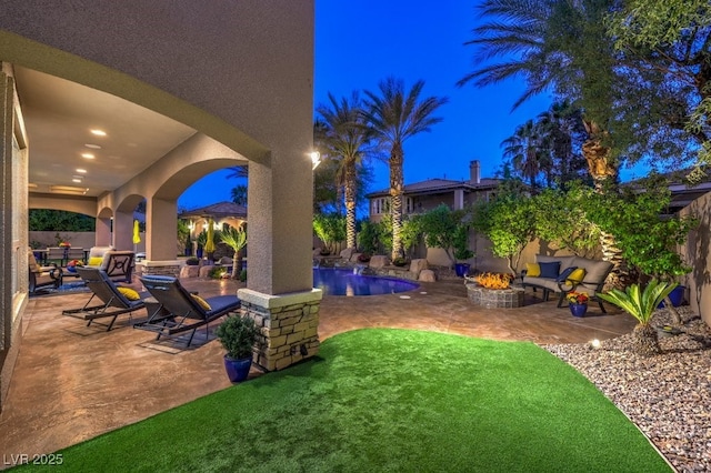 patio at twilight with a fenced backyard, an outdoor fire pit, and an outdoor pool