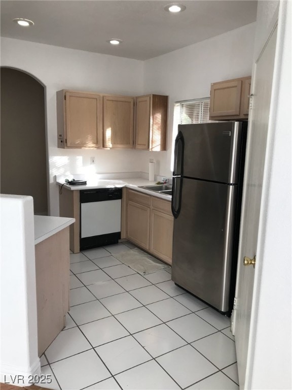 kitchen with freestanding refrigerator, light countertops, light brown cabinetry, and dishwasher