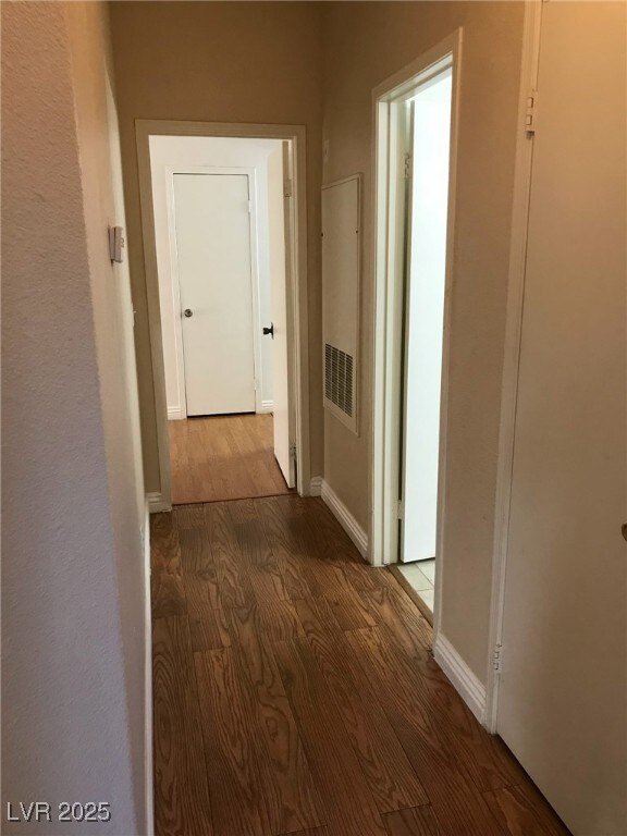 corridor featuring baseboards and wood finished floors