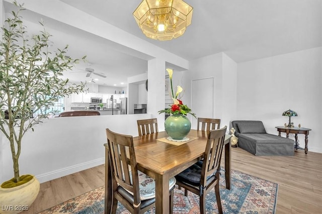 dining room featuring baseboards, a notable chandelier, and light wood-style flooring
