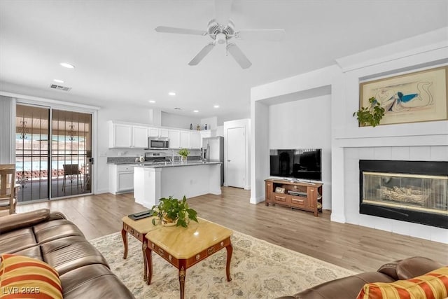 living room featuring light wood-style floors, recessed lighting, ceiling fan, and visible vents