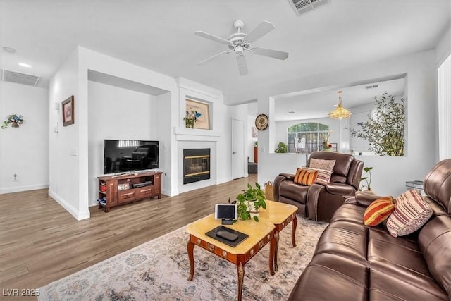 living room featuring visible vents, a ceiling fan, wood finished floors, and a fireplace