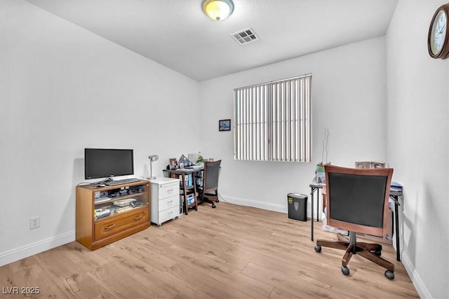 office area featuring baseboards, light wood-type flooring, and visible vents