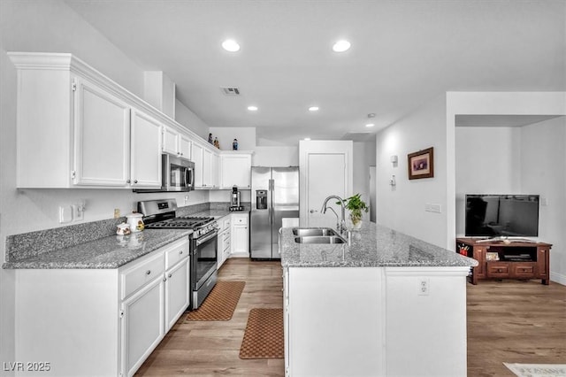 kitchen featuring white cabinets, a sink, light wood-style floors, stainless steel appliances, and visible vents