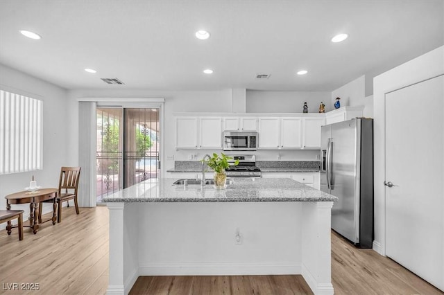 kitchen with visible vents, a sink, light wood-style flooring, and stainless steel appliances