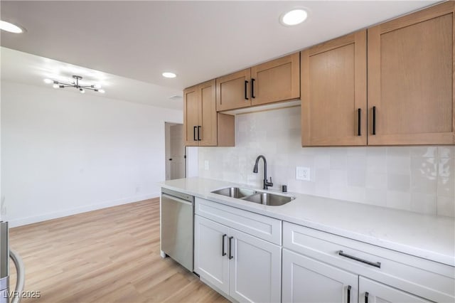 kitchen featuring a sink, dishwasher, light countertops, baseboards, and decorative backsplash
