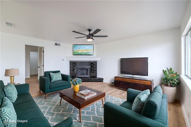 living room with visible vents, ceiling fan, and wood finished floors