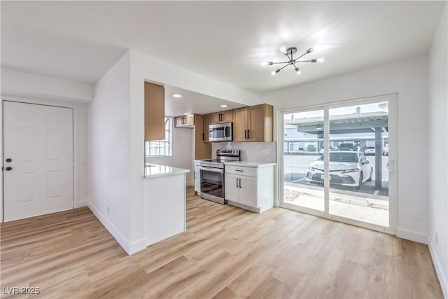 kitchen with an inviting chandelier, baseboards, appliances with stainless steel finishes, and light wood finished floors
