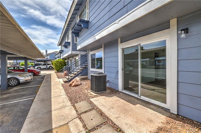 view of home's exterior with central AC unit and covered and uncovered parking
