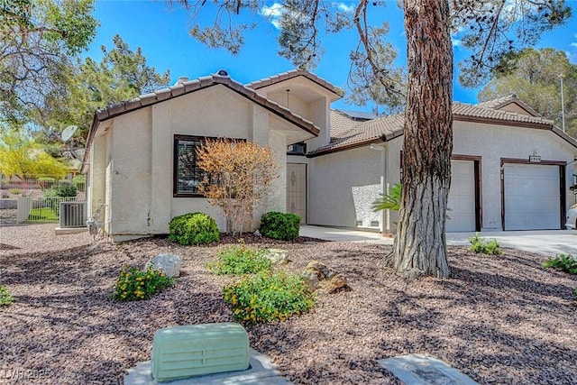 view of front of house with a garage, stucco siding, a tiled roof, and driveway
