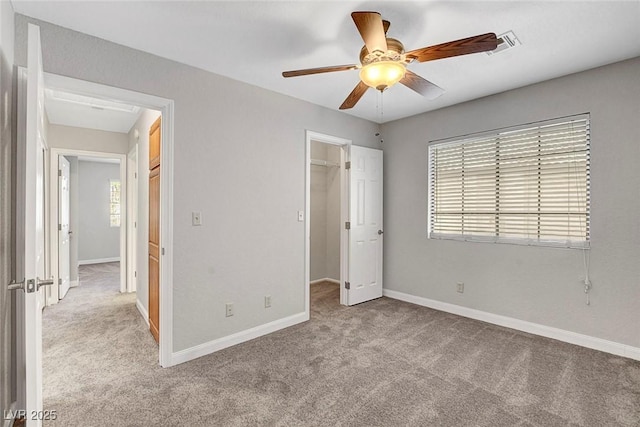 unfurnished bedroom featuring carpet floors, baseboards, a spacious closet, and a closet