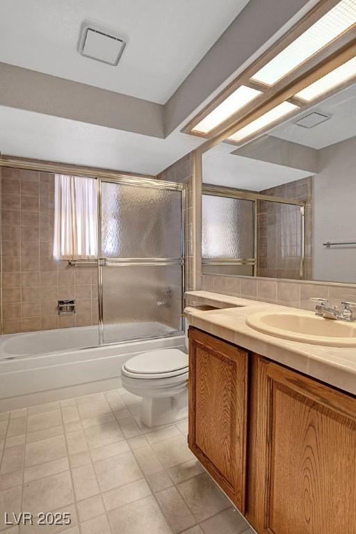 full bathroom featuring vanity, shower / bath combination with glass door, and toilet
