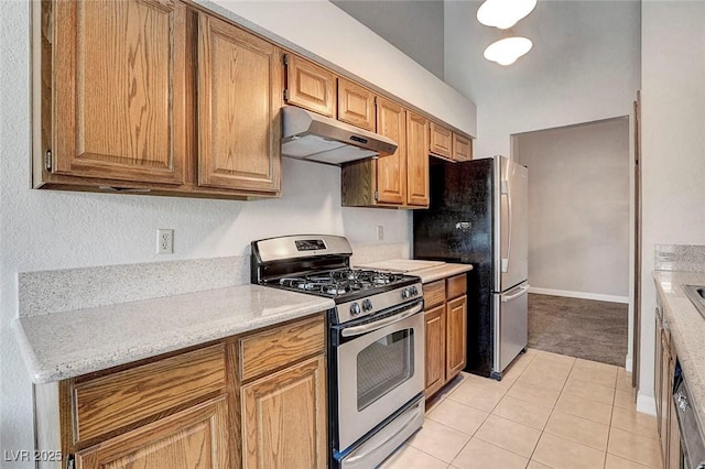 kitchen featuring appliances with stainless steel finishes, light countertops, light tile patterned floors, light carpet, and under cabinet range hood