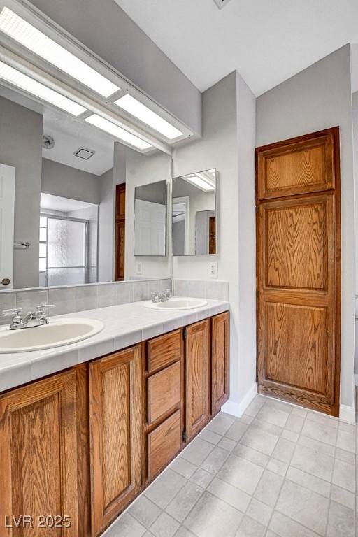full bathroom featuring a sink, baseboards, tile patterned floors, and double vanity