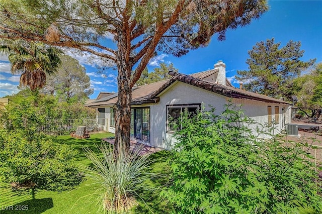 view of side of home featuring fence, stucco siding, and a chimney