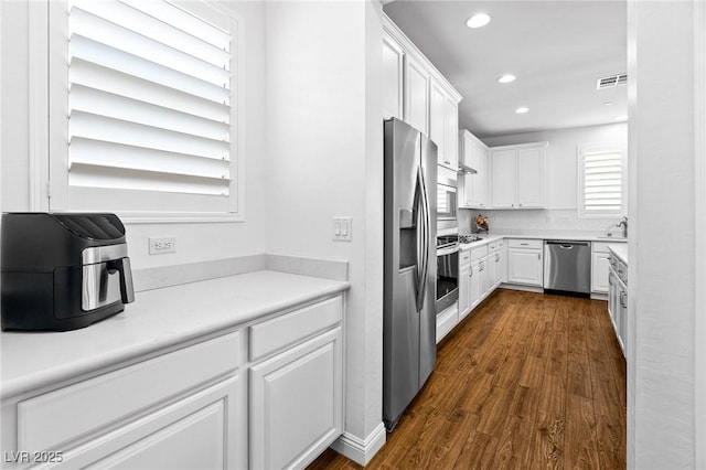 kitchen with stainless steel appliances, white cabinetry, recessed lighting, dark wood-style floors, and tasteful backsplash