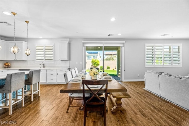 dining room featuring light wood finished floors, recessed lighting, and baseboards