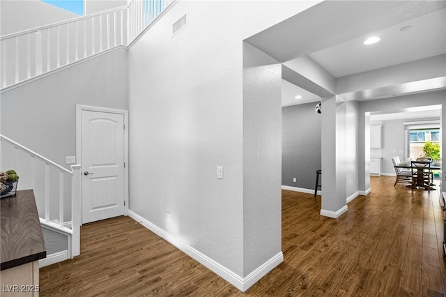 hall featuring wood finished floors, stairway, baseboards, and recessed lighting