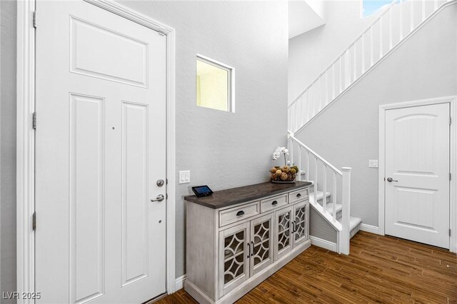 entryway with stairway, dark wood-style floors, and baseboards
