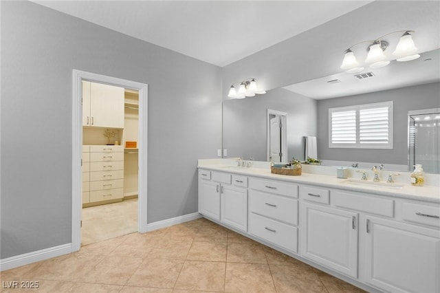 full bath featuring double vanity, baseboards, a spacious closet, and tile patterned floors