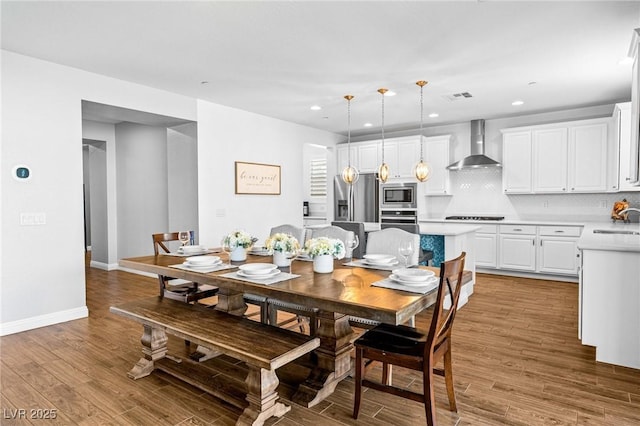 dining space with baseboards, light wood finished floors, and recessed lighting