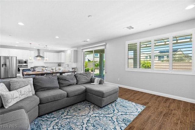 living area with recessed lighting, dark wood-type flooring, and baseboards