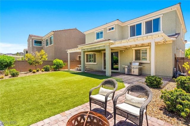 rear view of property featuring stucco siding, a fire pit, a patio, and exterior kitchen