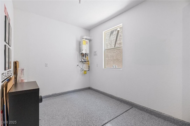 unfurnished room with speckled floor, baseboards, and water heater