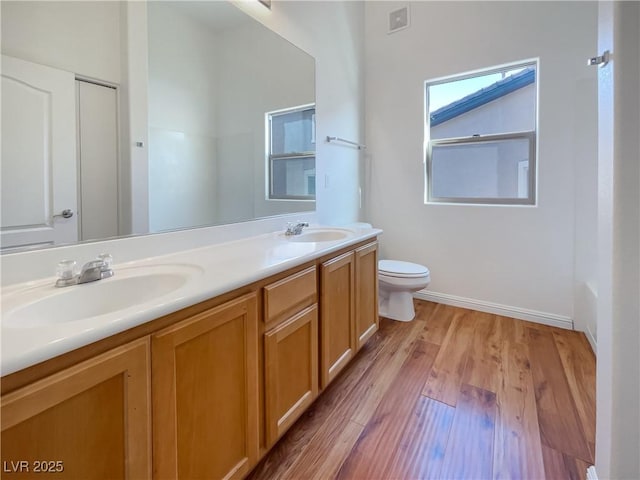 full bath featuring toilet, visible vents, a sink, and wood finished floors