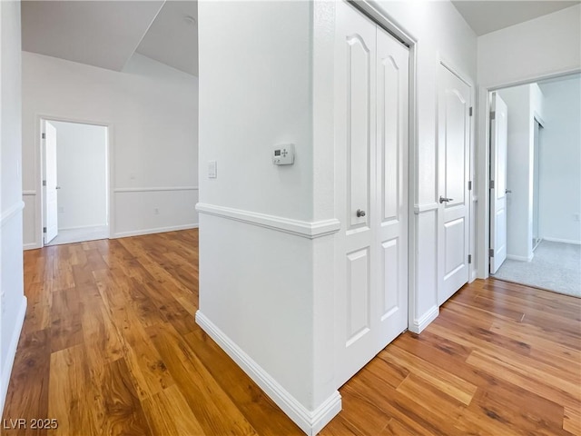 hall with light wood-type flooring and baseboards