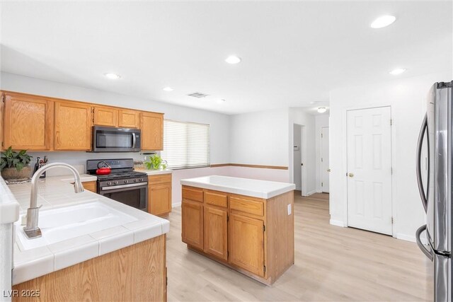 kitchen with visible vents, appliances with stainless steel finishes, a sink, and light wood-style flooring