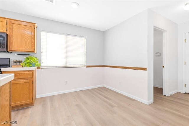 kitchen with light countertops, baseboards, stove, and light wood-style flooring