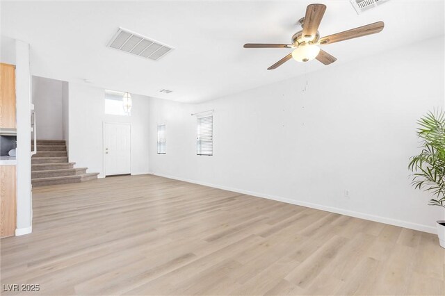 unfurnished room with visible vents, light wood finished floors, ceiling fan, and stairway