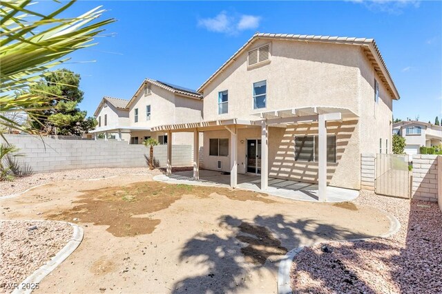 back of house with a fenced backyard, a pergola, stucco siding, and a patio area