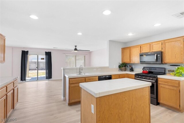 kitchen featuring a sink, gas stove, a peninsula, light wood-type flooring, and visible vents