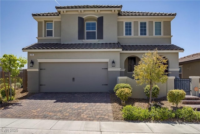 mediterranean / spanish-style house featuring stucco siding, decorative driveway, a tile roof, and a garage
