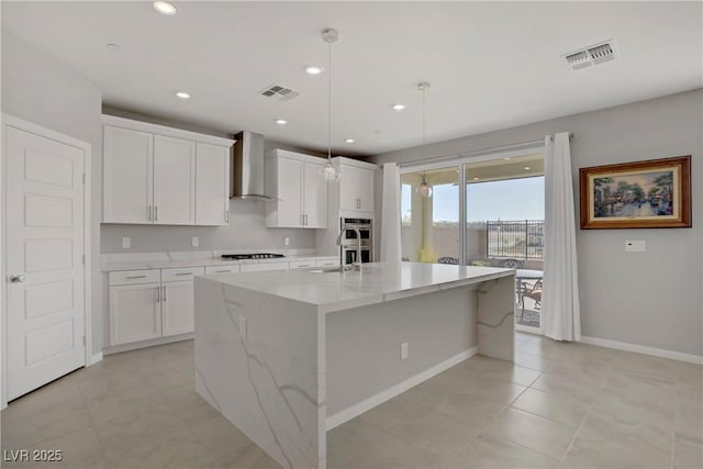 kitchen with wall chimney range hood, baseboards, stovetop, and visible vents