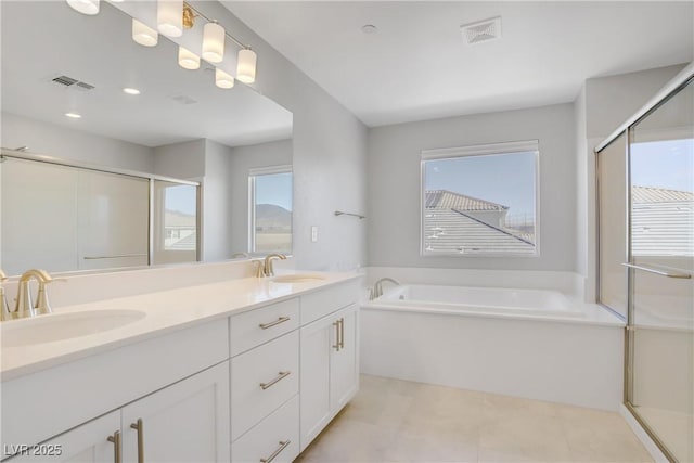 bathroom with double vanity, visible vents, a sink, and a bath