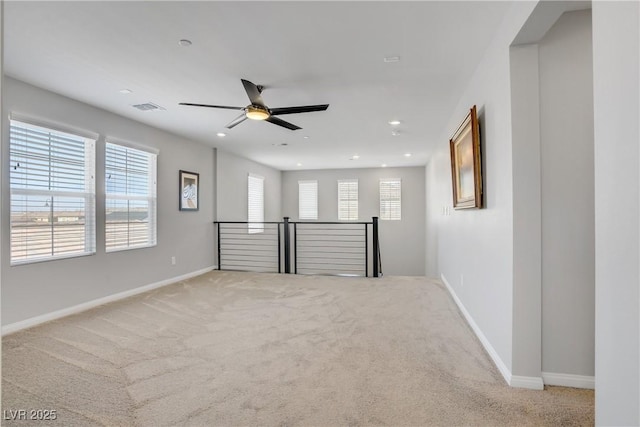 carpeted empty room with ceiling fan, visible vents, plenty of natural light, and baseboards