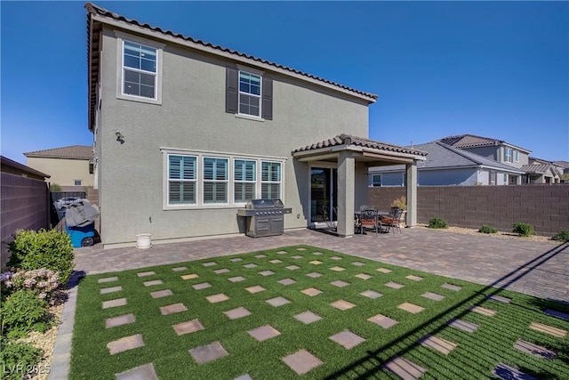 back of house with a lawn, a fenced backyard, a patio area, and stucco siding