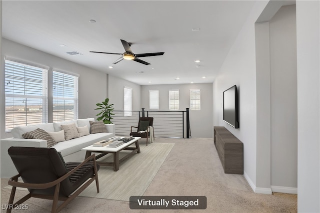 living room featuring ceiling fan, visible vents, plenty of natural light, and light carpet