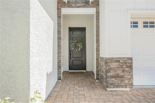 property entrance with stucco siding and stone siding