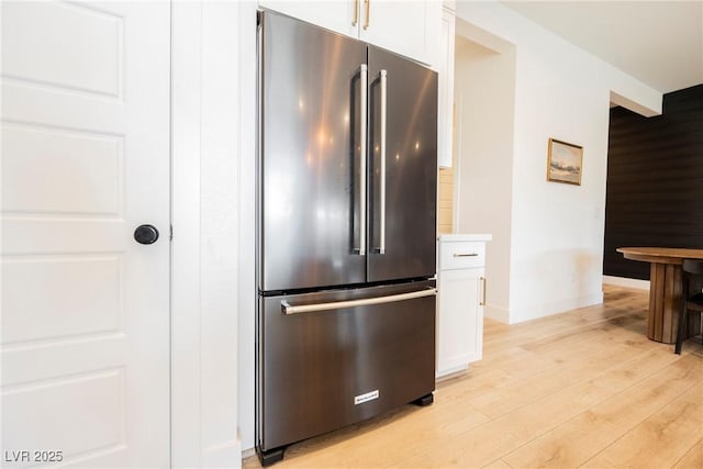kitchen featuring high end fridge, light countertops, light wood-style flooring, white cabinetry, and baseboards