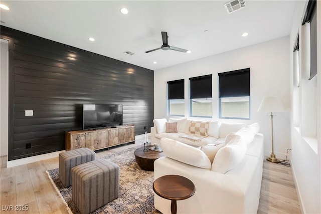 living room featuring an accent wall, a ceiling fan, recessed lighting, and visible vents