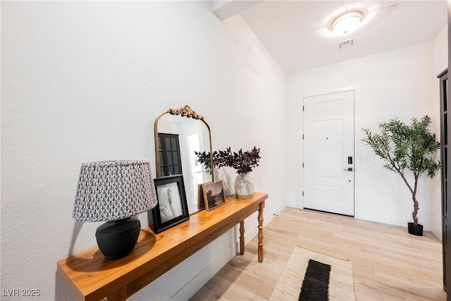 foyer entrance with visible vents, light wood finished floors, and baseboards