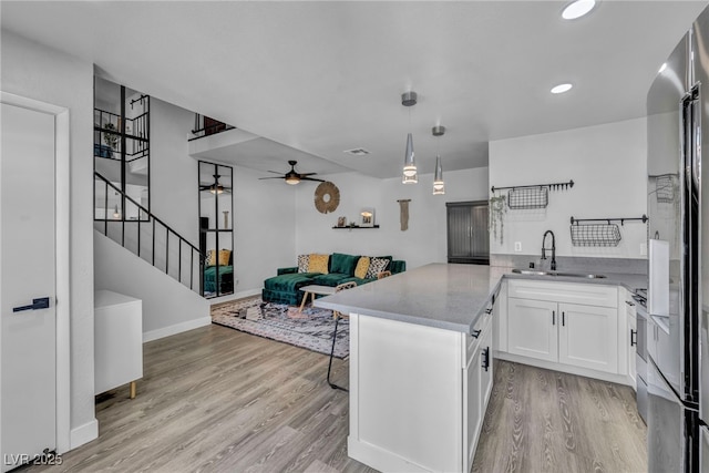 kitchen with a sink, white cabinetry, ceiling fan, and light wood finished floors