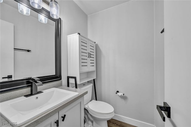 half bath featuring toilet, baseboards, wood finished floors, and vanity