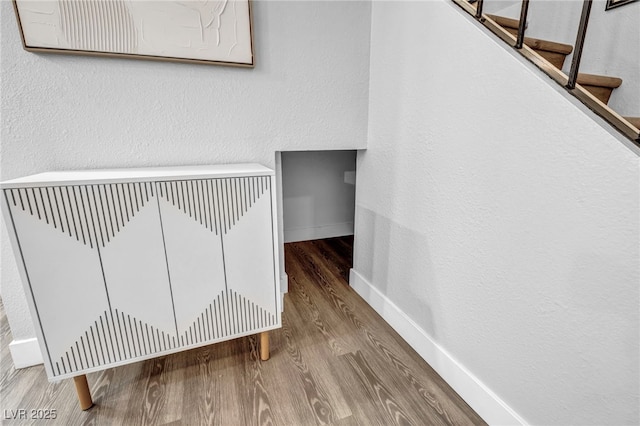 stairway with baseboards, heating unit, and wood finished floors