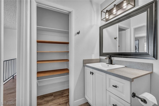 bathroom with baseboards, wood finished floors, and vanity