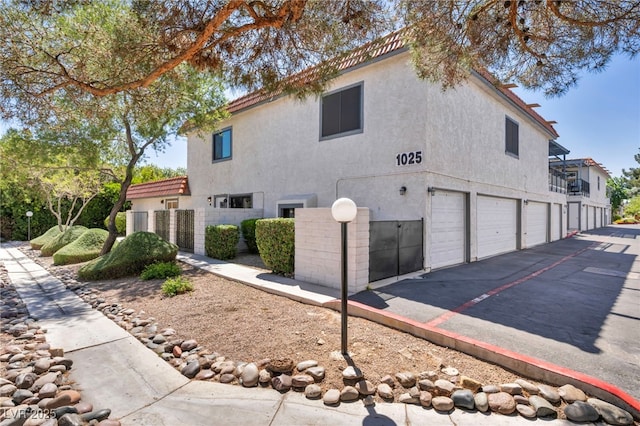 view of side of property with a garage, driveway, and stucco siding